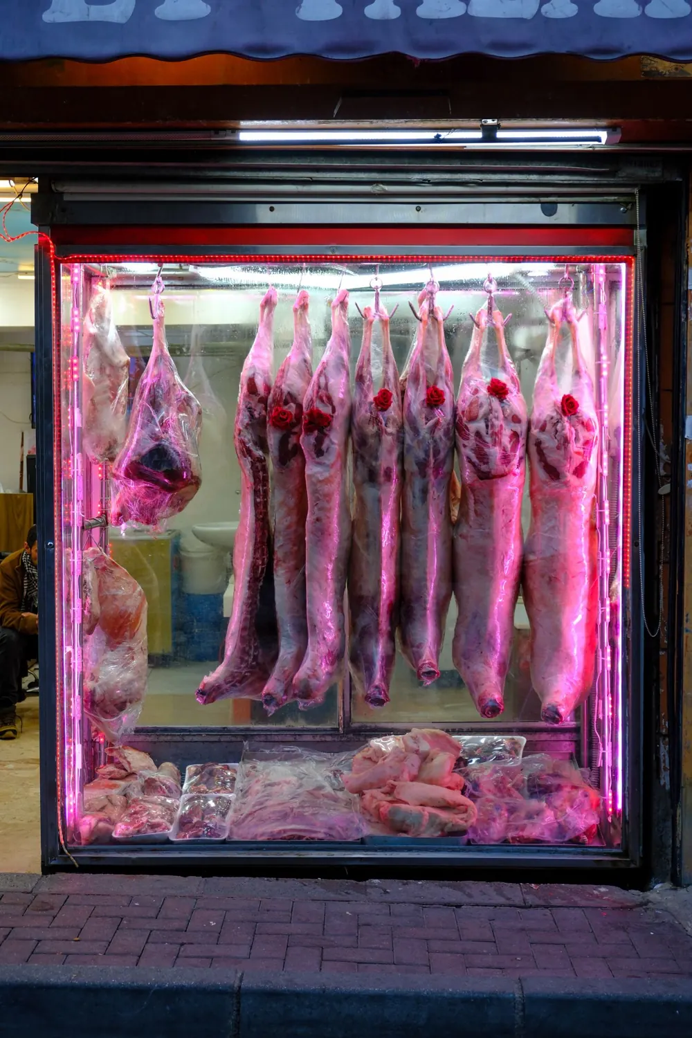 Vitrine de maturation, pièces de viande suspendues sous une lumière rose